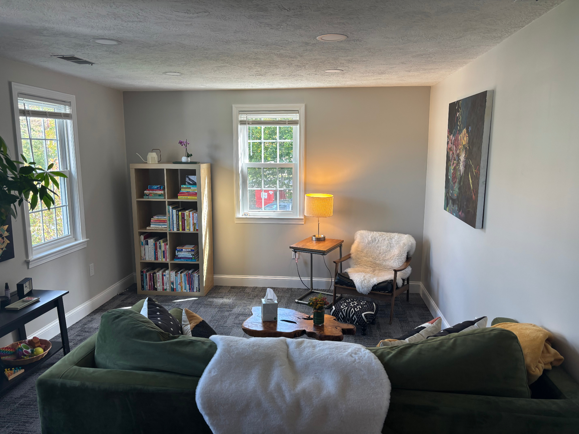 Counseling office sitting area with green sofa and bookshelf